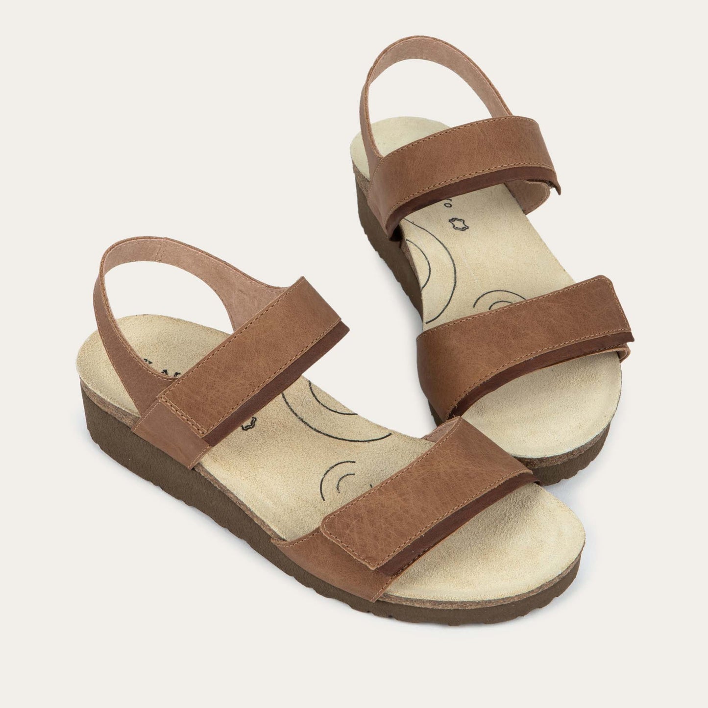 A pair of brown leather sandals with two toe straps, an adjustable ankle strap, and a cork platform sole.