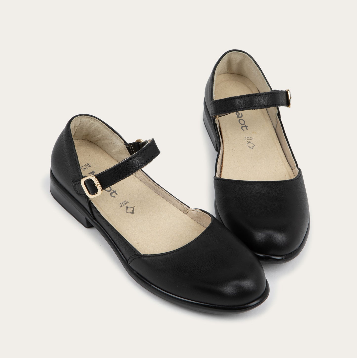 A pair of of a black maryjanes with a simple buckle strap on a black and brown sole