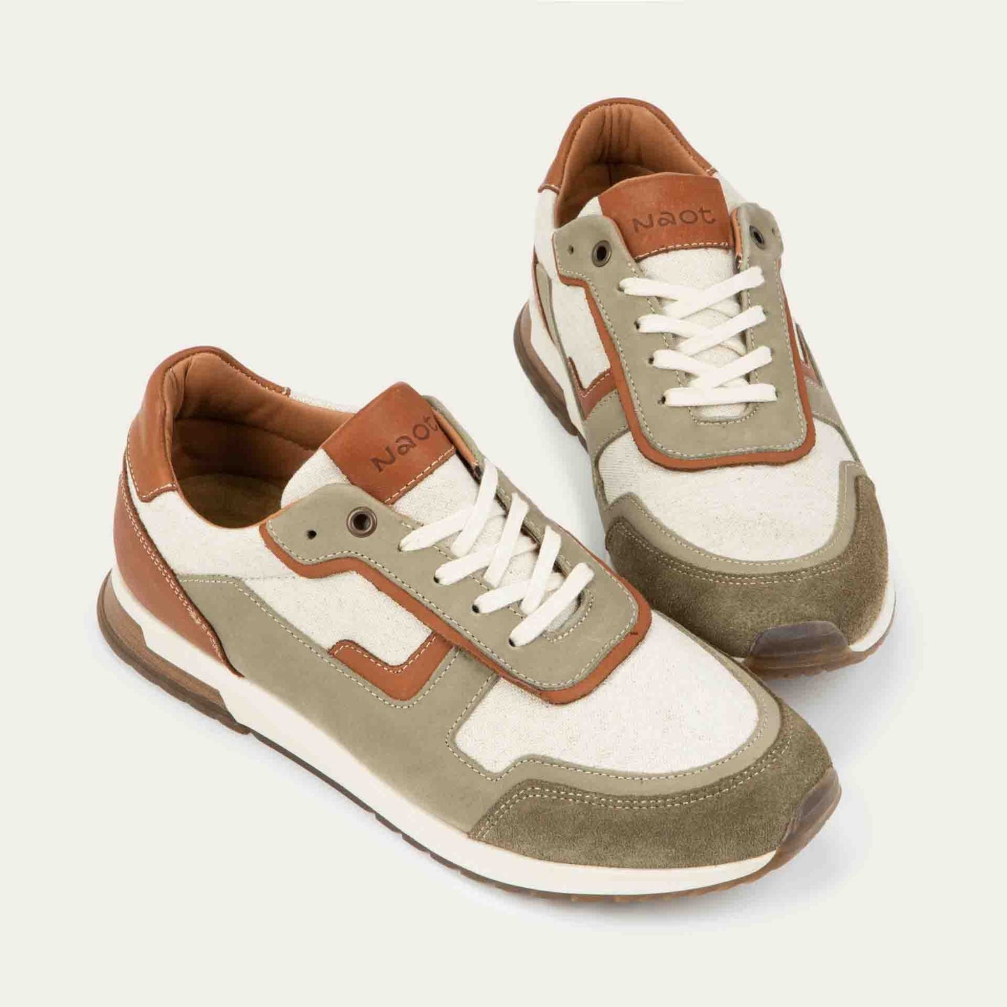 Pair of green and beige sneakers featuring different materials on a white sole