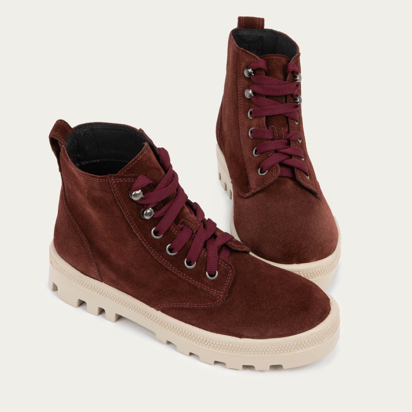 Pair of violet textured suede high-top boots with violet laces and a light beige sole.
