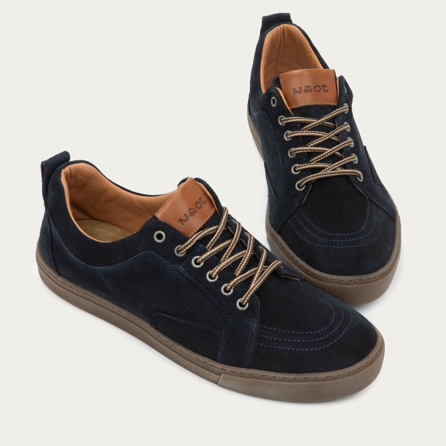 Pair of black low-top sneakers with tan laces, brown soles, and tan interior linings.