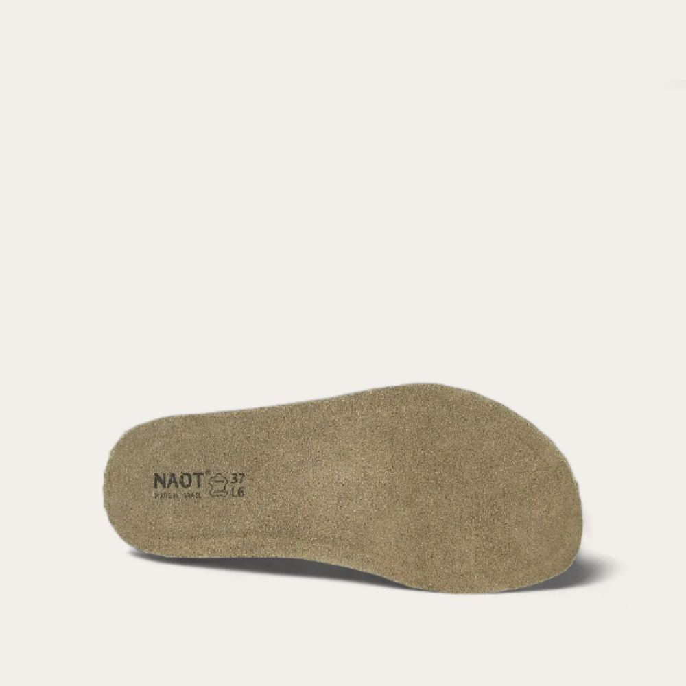 A top-down view of a beige-colored, cork and suede footbed with the brand 'NAOT' printed on it.