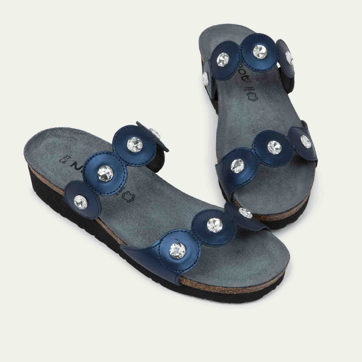 Pair of navy blue sandals with cork wedge sole. Features two straps with circular details and large round silver studs.