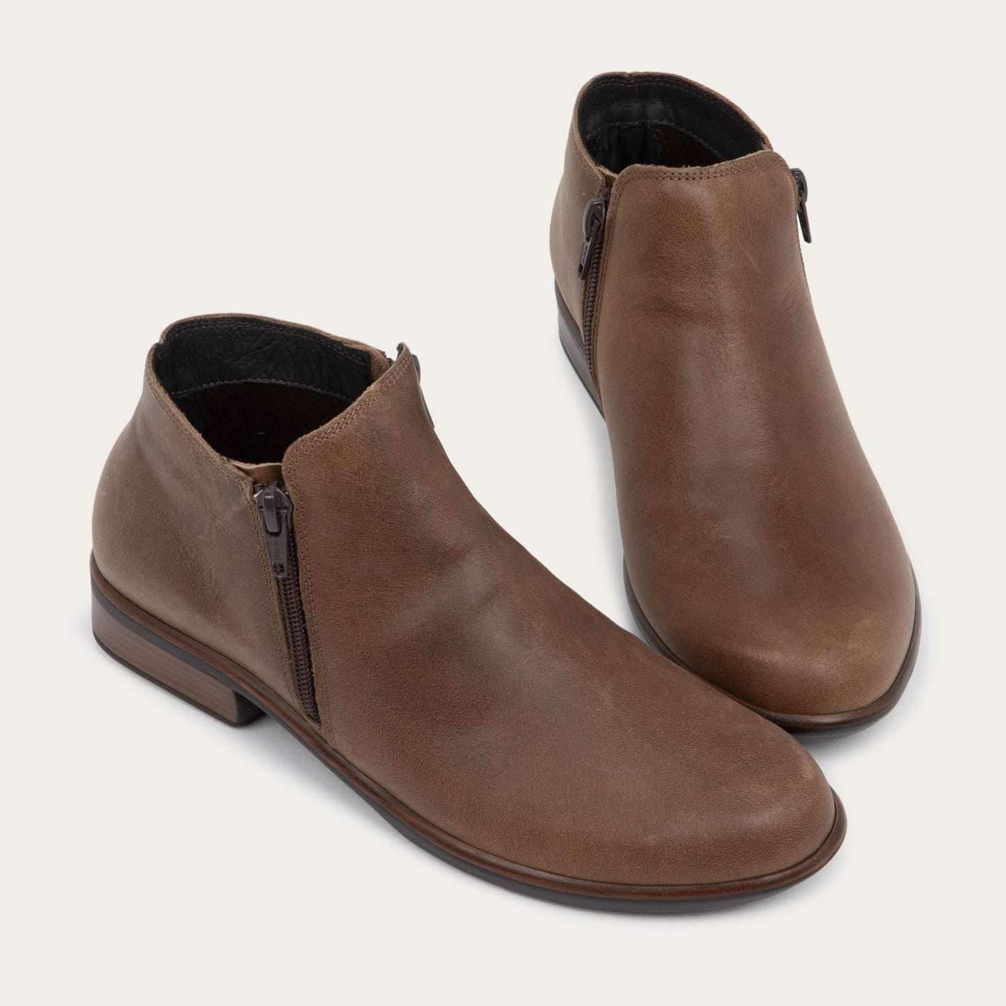 A pair of a brown booties with a black and brown sole.
