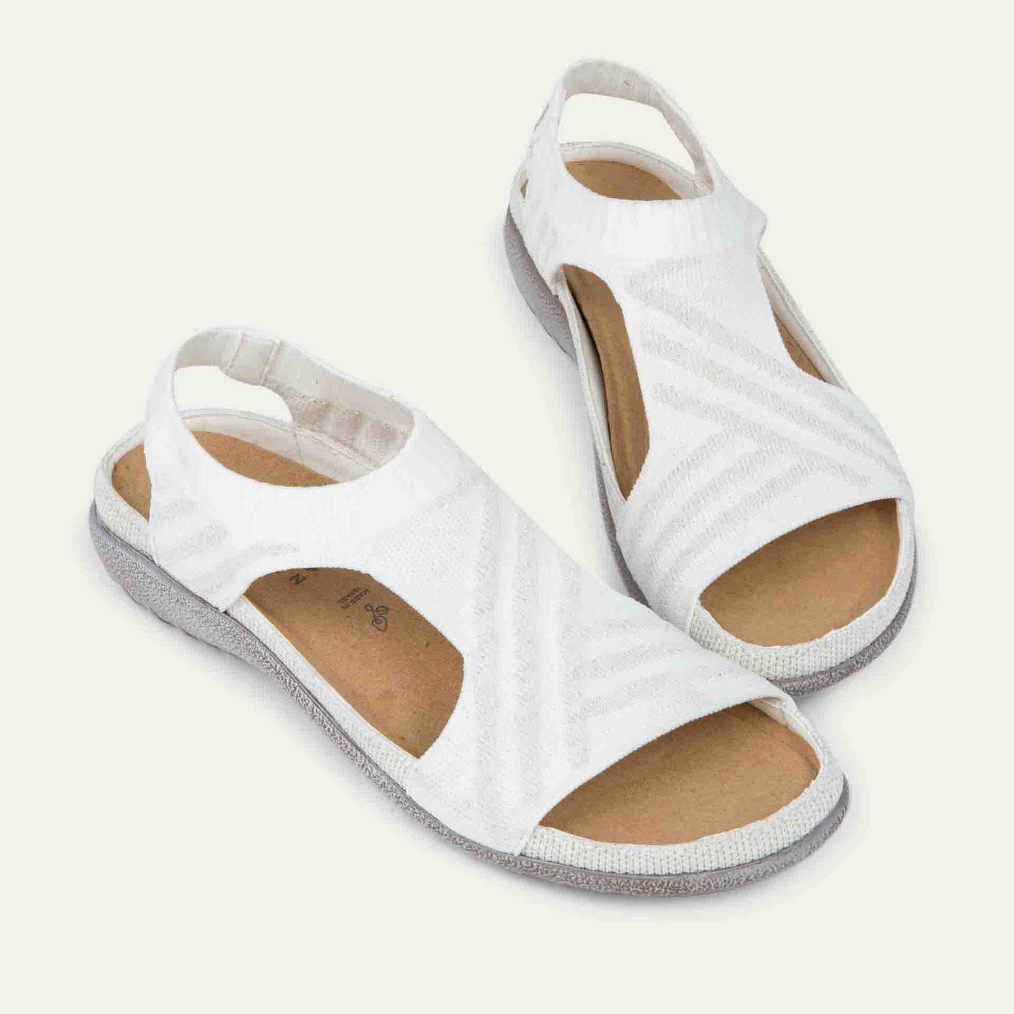 Pair of white sparkle knit cutout sandals with open toes, elastic ankle strap, and black textured sole.