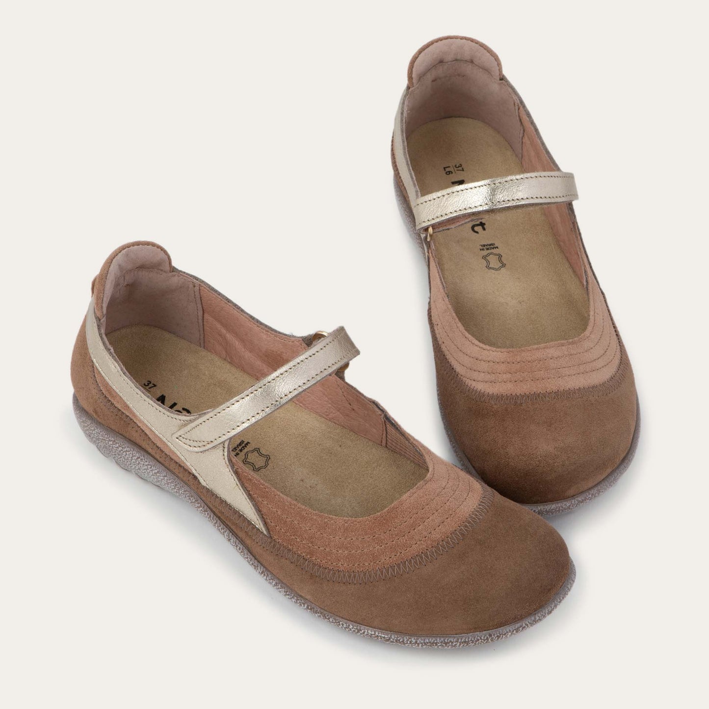Pair of brown Mary Jane flats with metallic straps, suede uppers, textured soles, and a comfortable casual design on a plain white background.