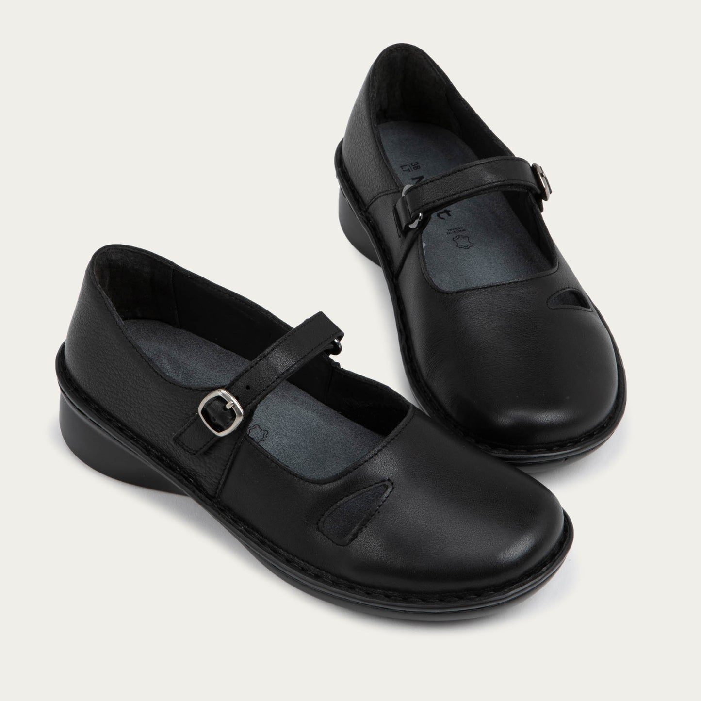Pair of black maryjanes on a black sole featuring a simple buckle and small cutout detail on the side