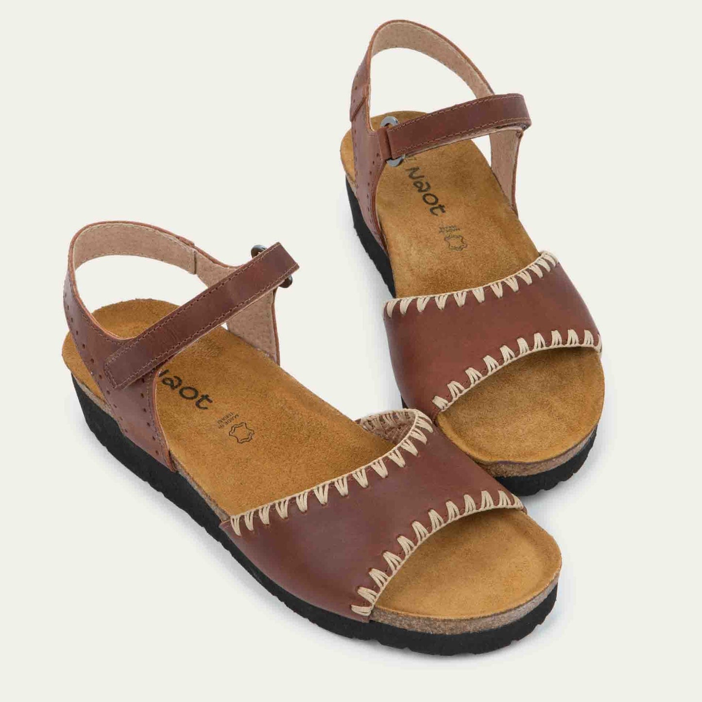 Pair of brown sandals featuring a toe strap with contrast stitiching, adjustable ankle strap, and a cork footbed.