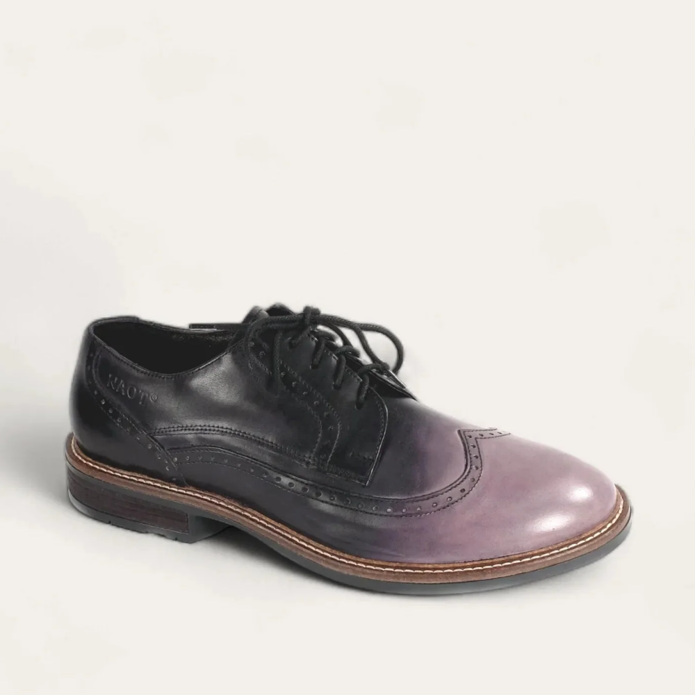 A black and brown handcrafted leather wingtip shoe with a lace-up closure.