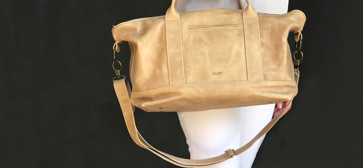 A tan leather duffel bag with top handles and a shoulder strap.