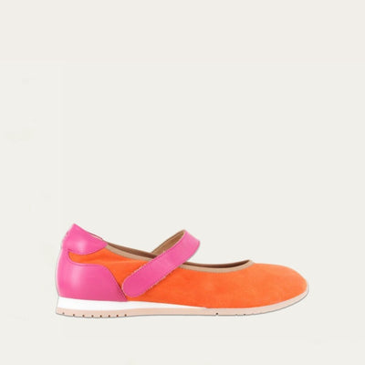 Profile view of a orange suede mary jane featuring pink leather accents on a low white and beige sole.