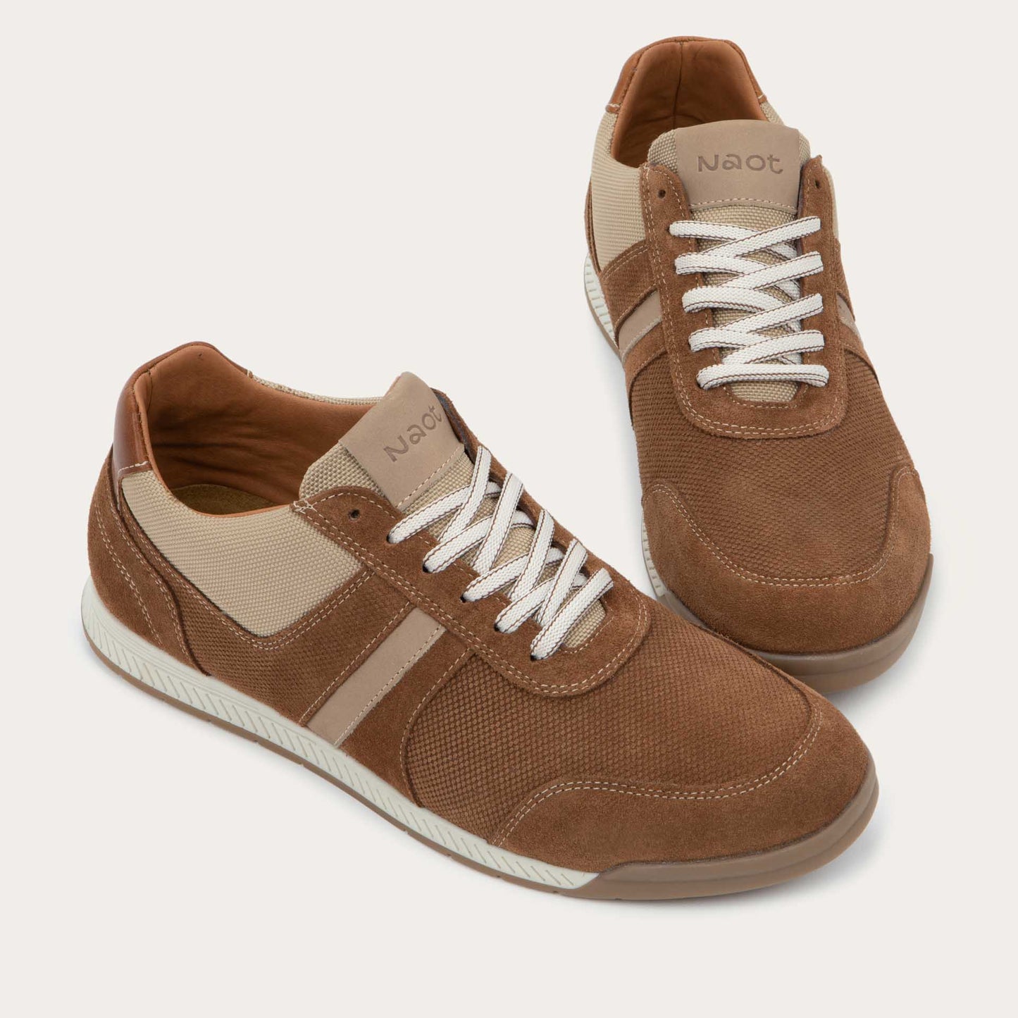 Pair of brown and beige sneakers on a brown sole.