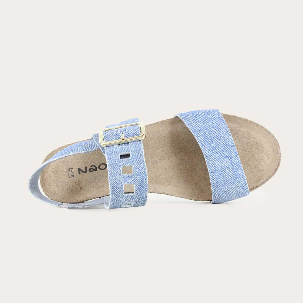 Top view of a blue denim wedge sandal, featuring two straps and a metallic buckle with a cork footbed.