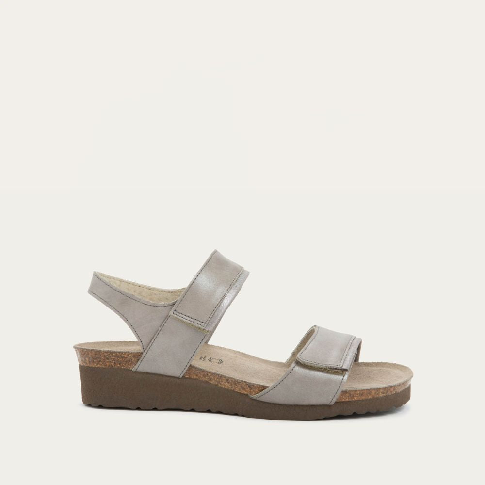 Profile view of a silver leather sandal with two adjustable straps and a cork platform sole.