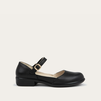 Profile view of a black maryjane with a simple buckle strap on a black and brown sole