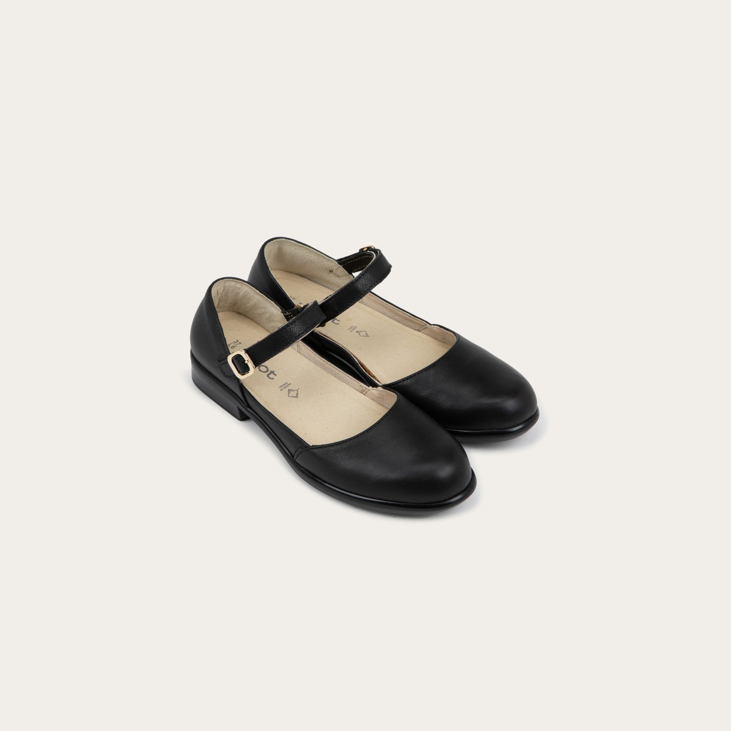 A pair of of a black maryjanes with a simple buckle strap on a black and brown sole
