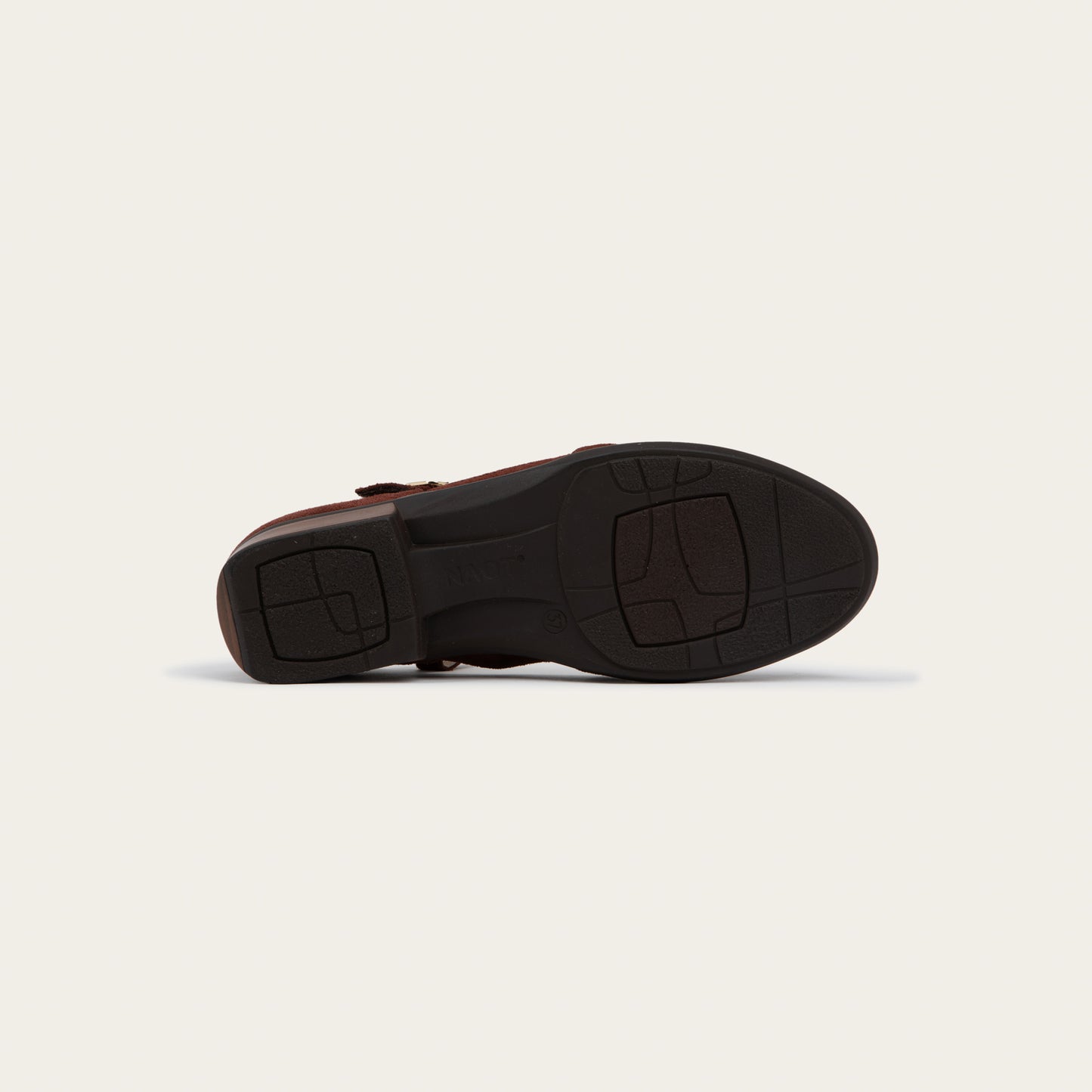 Bottom view of a red maryjane with a simple buckle strap on a black and brown sole