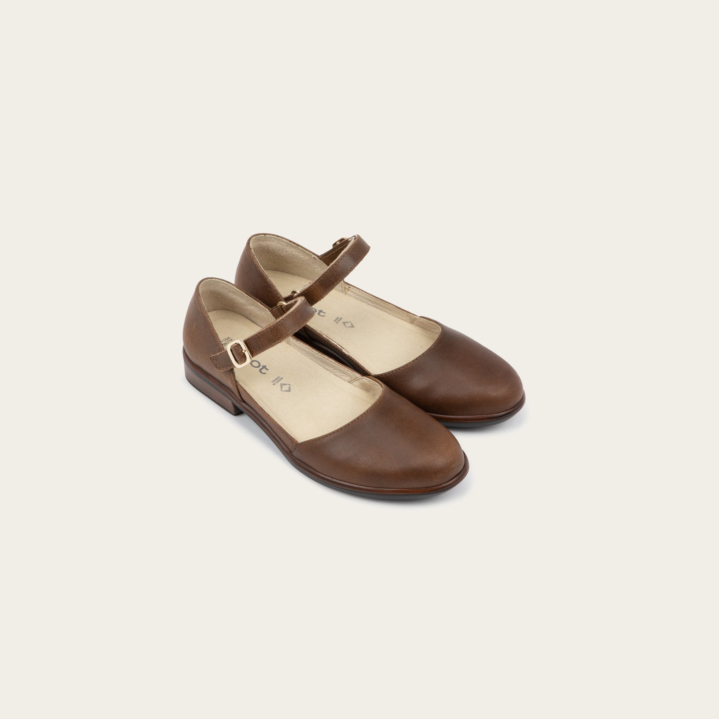 A pair of of a brown maryjanes with a simple buckle strap on a black and brown sole