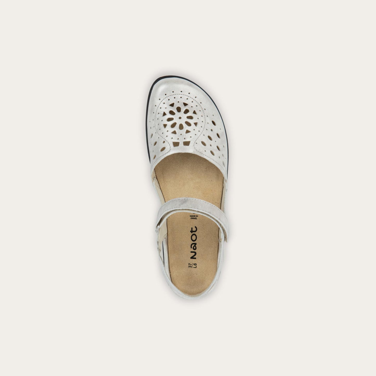 Top view of a silver flat shoe with a perforated design, open heel, and adjustable ankle strap on a black sole