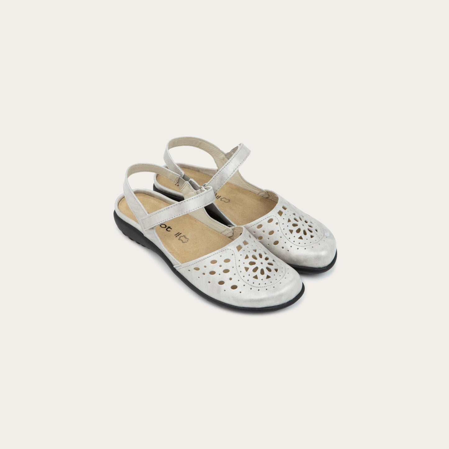 Pair of silver flat shoes with a perforated design, open heel, and adjustable ankle strap on a black sole