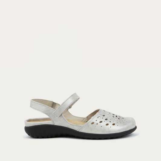 Profile view of a silver flat shoe with a perforated design, open heel, and adjustable ankle strap on a black sole