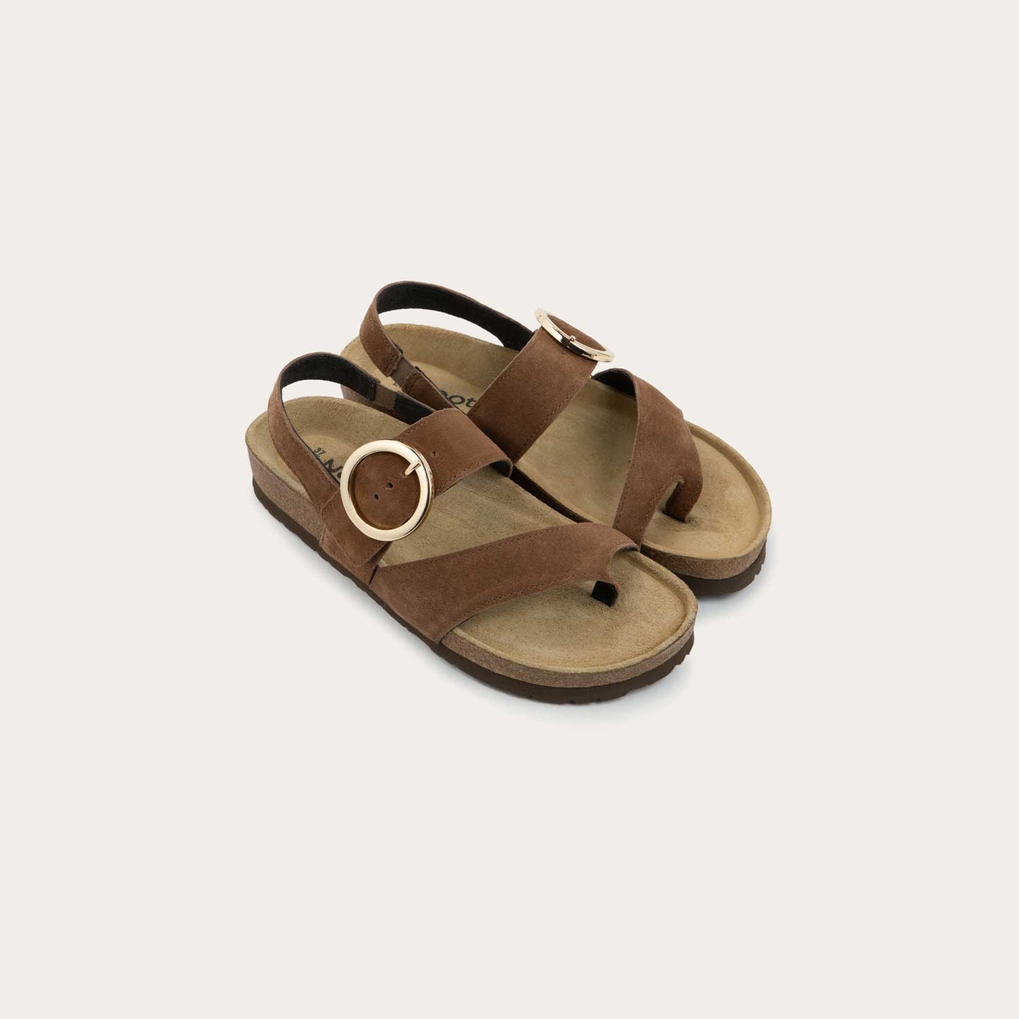 Pair of brown strappy slides with an oversized buckle and a toe thong, featuring a cork sole.