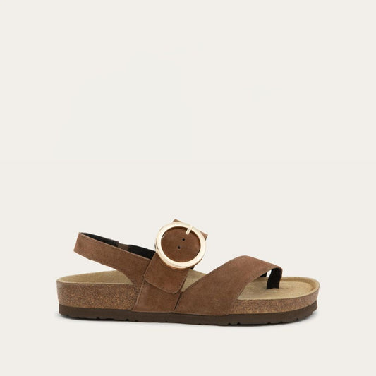 Profile view of a brown strappy slide with an oversized buckle and a toe thong, featuring a cork sole.