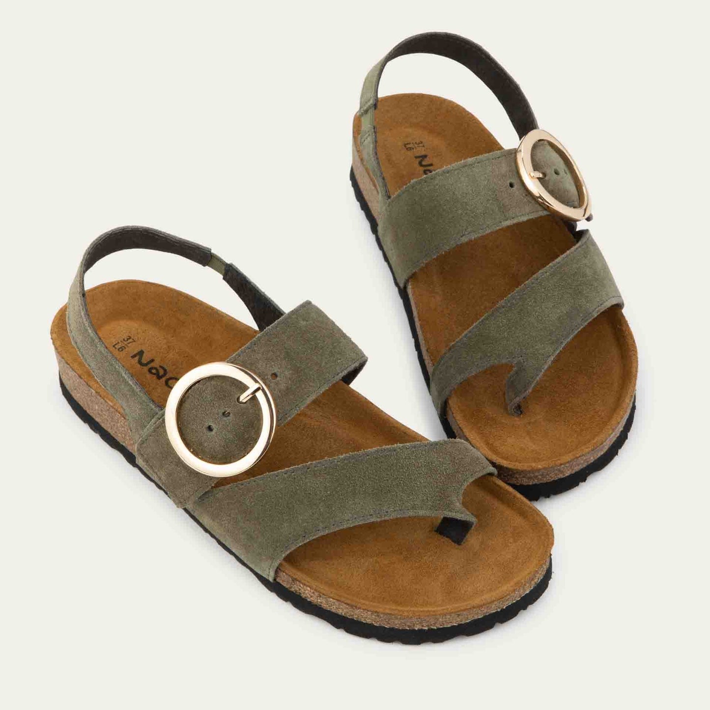 Pair of green strappy slides with an oversized buckle and a toe thong, featuring a cork sole.