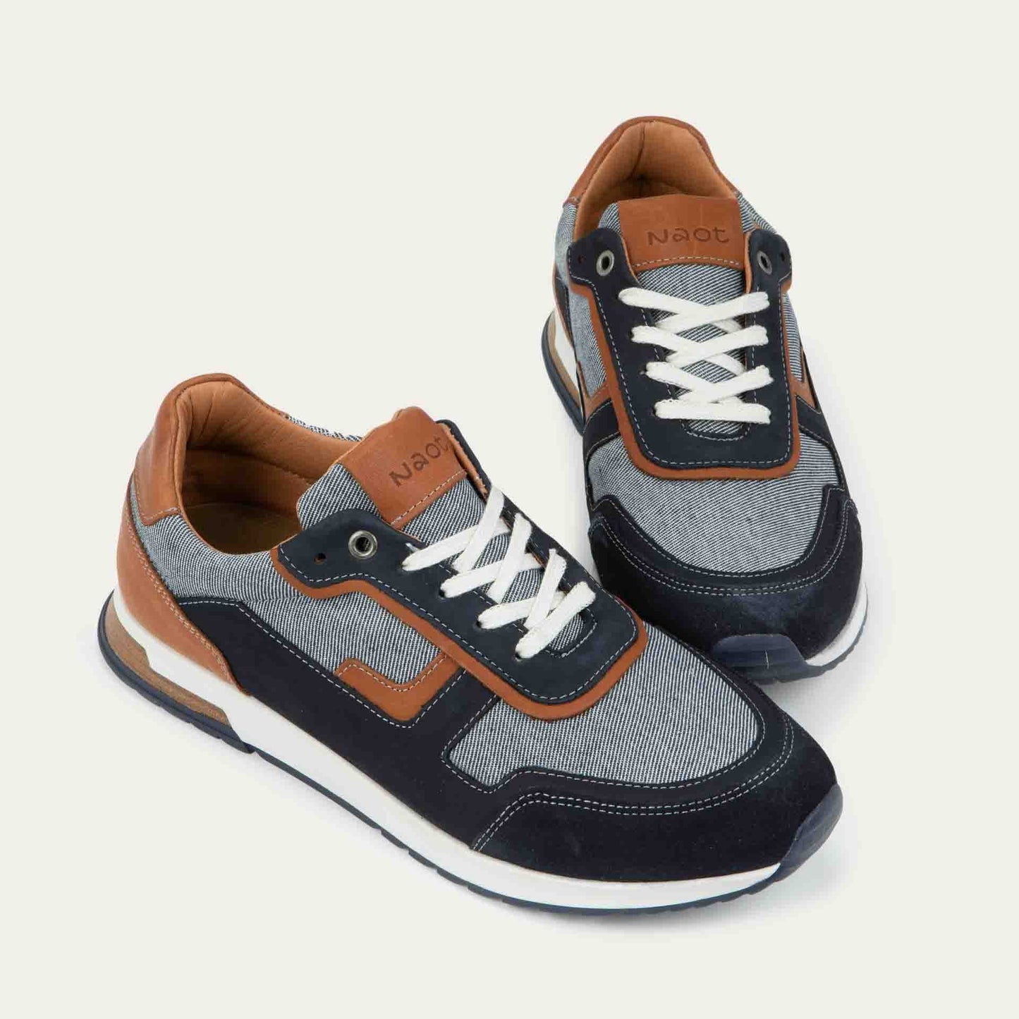 Pair of  blue and brown sneakers featuring different materials on a white sole