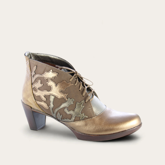 Gold ankle boot with decorative patterns on a light gray background