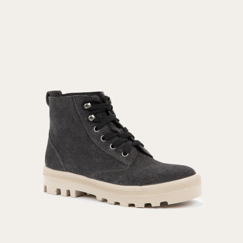 Angled profile view of a black textured suede high-top boot with black laces and a light beige sole. 