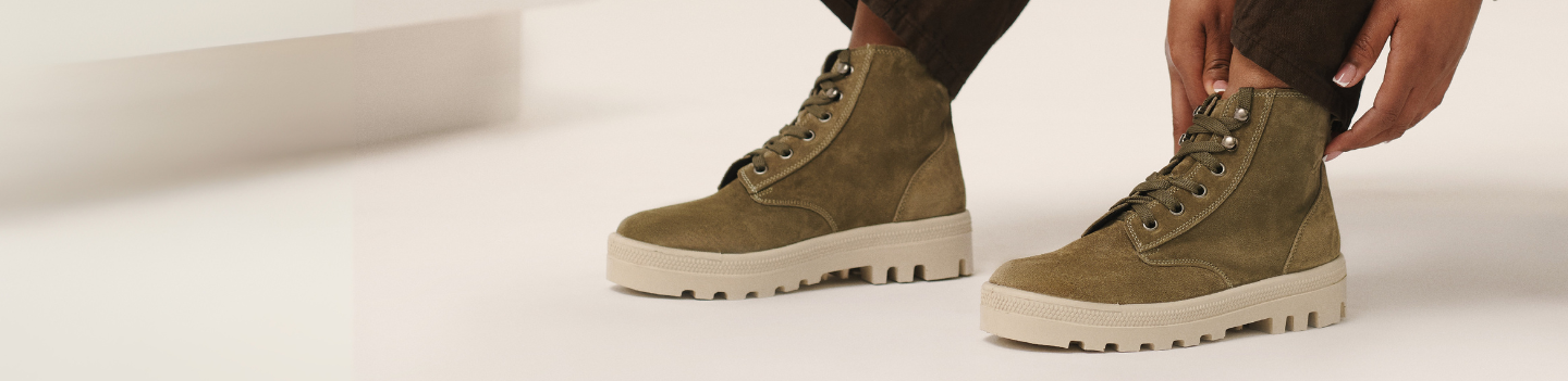 Close-up of green boots with white soles on a light background