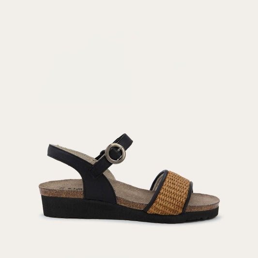 Profile view of a sandal with a black ankle strap and buckle, cork wedge sole, and a woven tan strap on the front. 