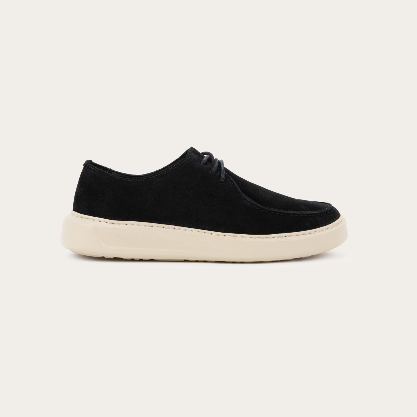 Profile view of a black suede lace-up shoe with a moccasin-style toe and a thick, cream-colored rubber sole.