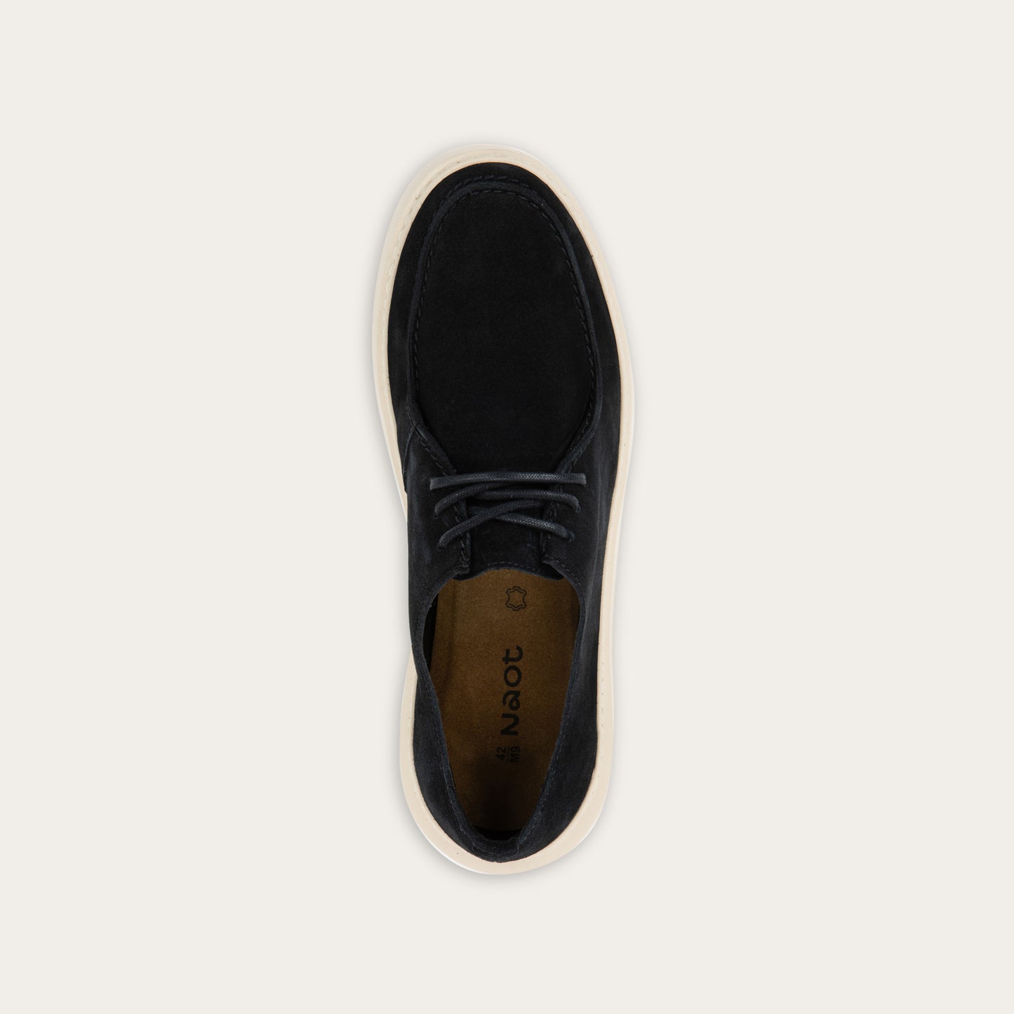 Top view of a black suede lace-up shoe with a moccasin-style toe and a thick, cream-colored rubber sole.