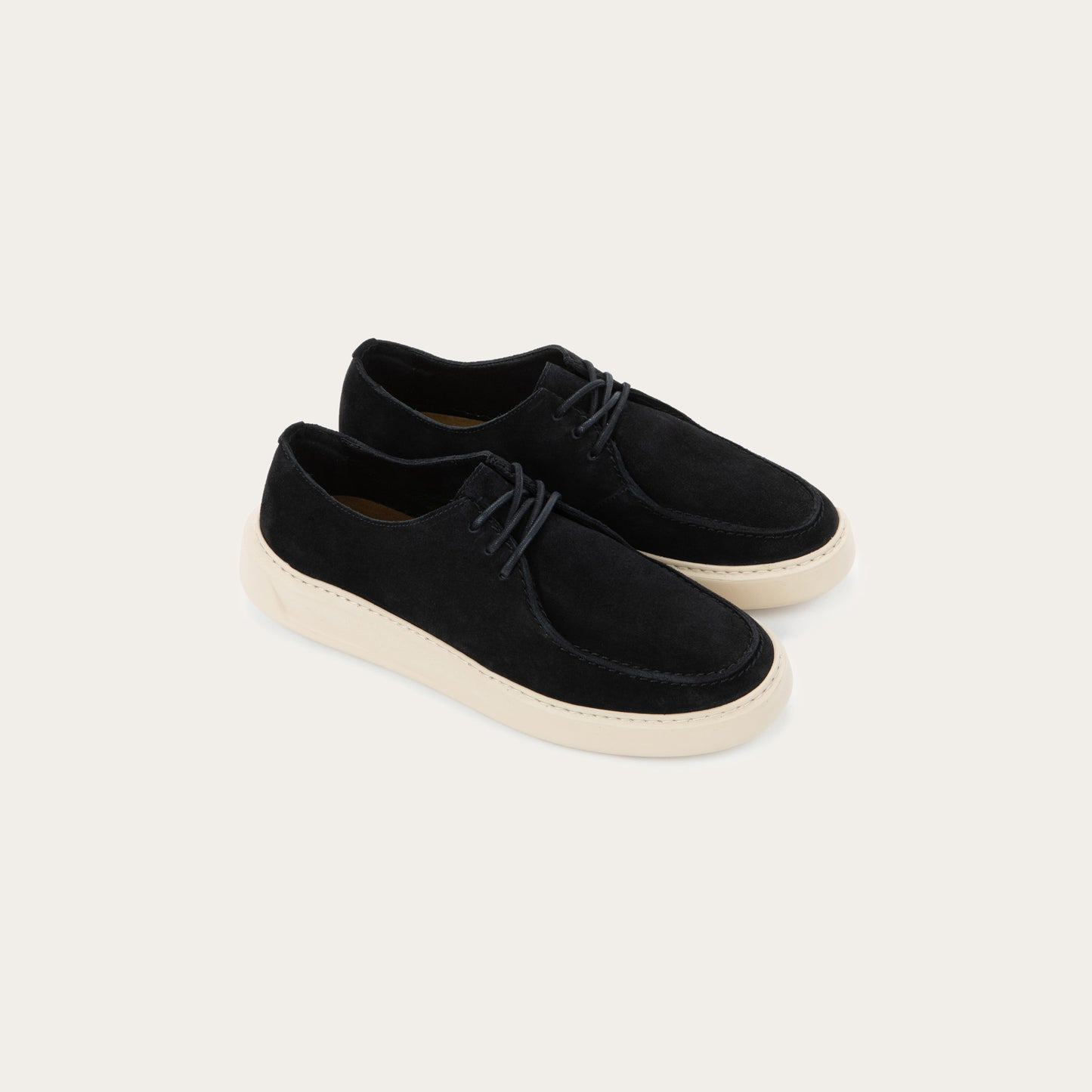 Pair of black suede lace-up shoe with a moccasin-style toe and a thick, cream-colored rubber sole.