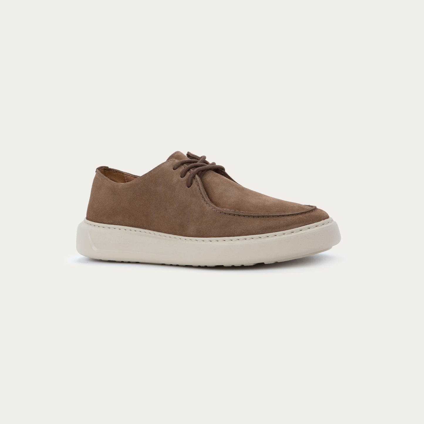 Angled profile view of a brown suede lace-up shoe with a thick, off-white rubber sole, featuring a stitched toe and a clean, minimalist design.