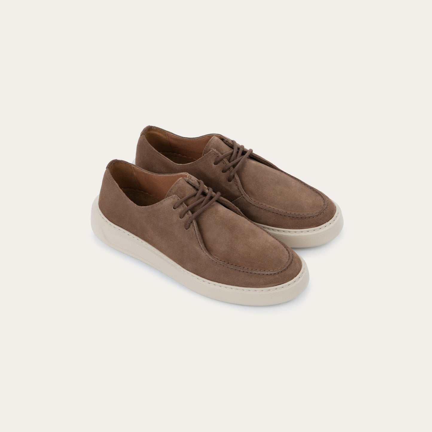 Pair of  brown suede lace-up shoes with a thick, off-white rubber soles, featuring astitched toes and clean, minimalist designs.