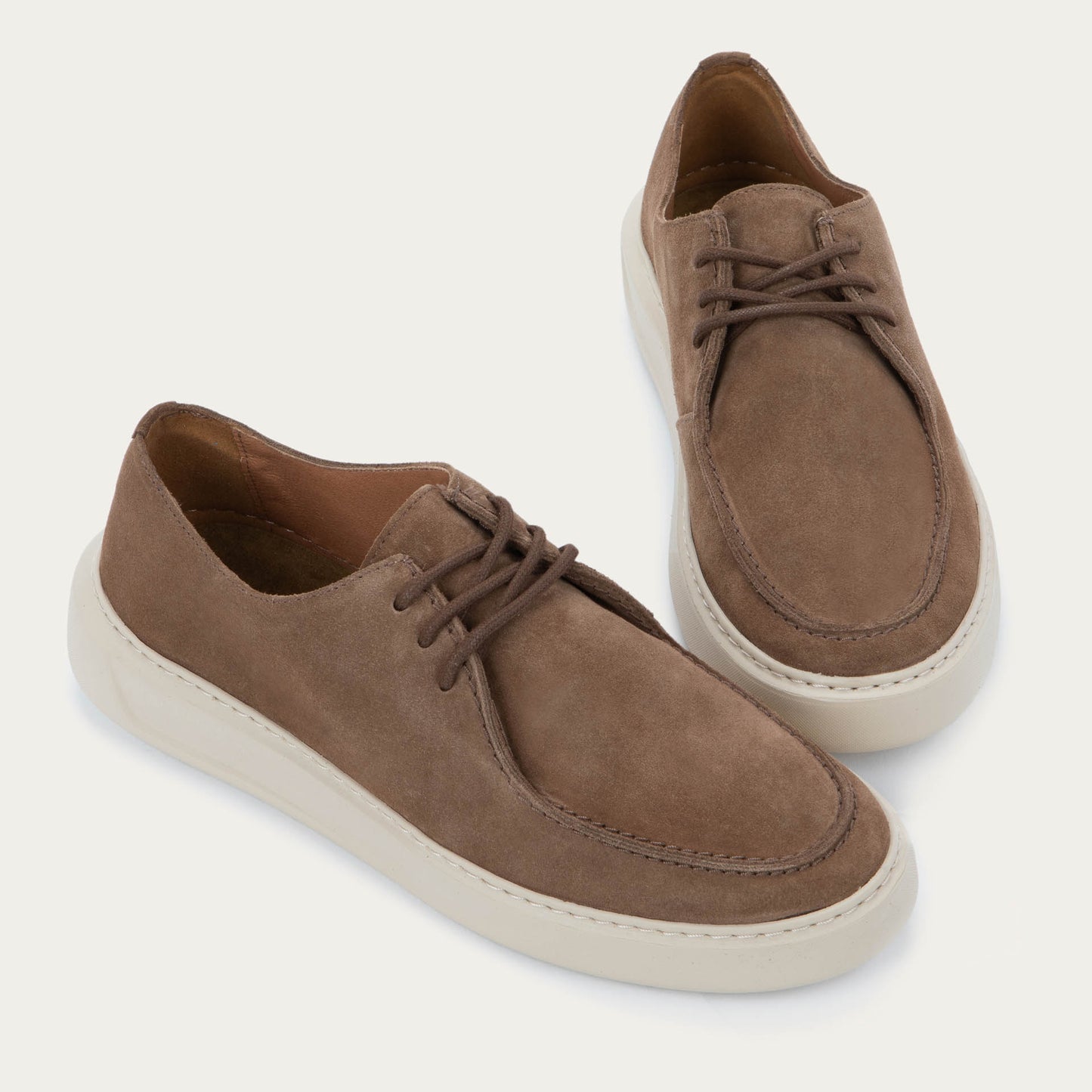 Pair of  brown suede lace-up shoes with a thick, off-white rubber soles, featuring astitched toes and clean, minimalist designs.