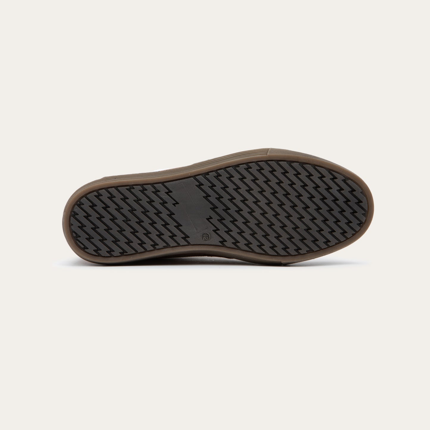 Bottom view of a brown suede and perforated leather sneaker with matching brown laces and a textured rubber sole.