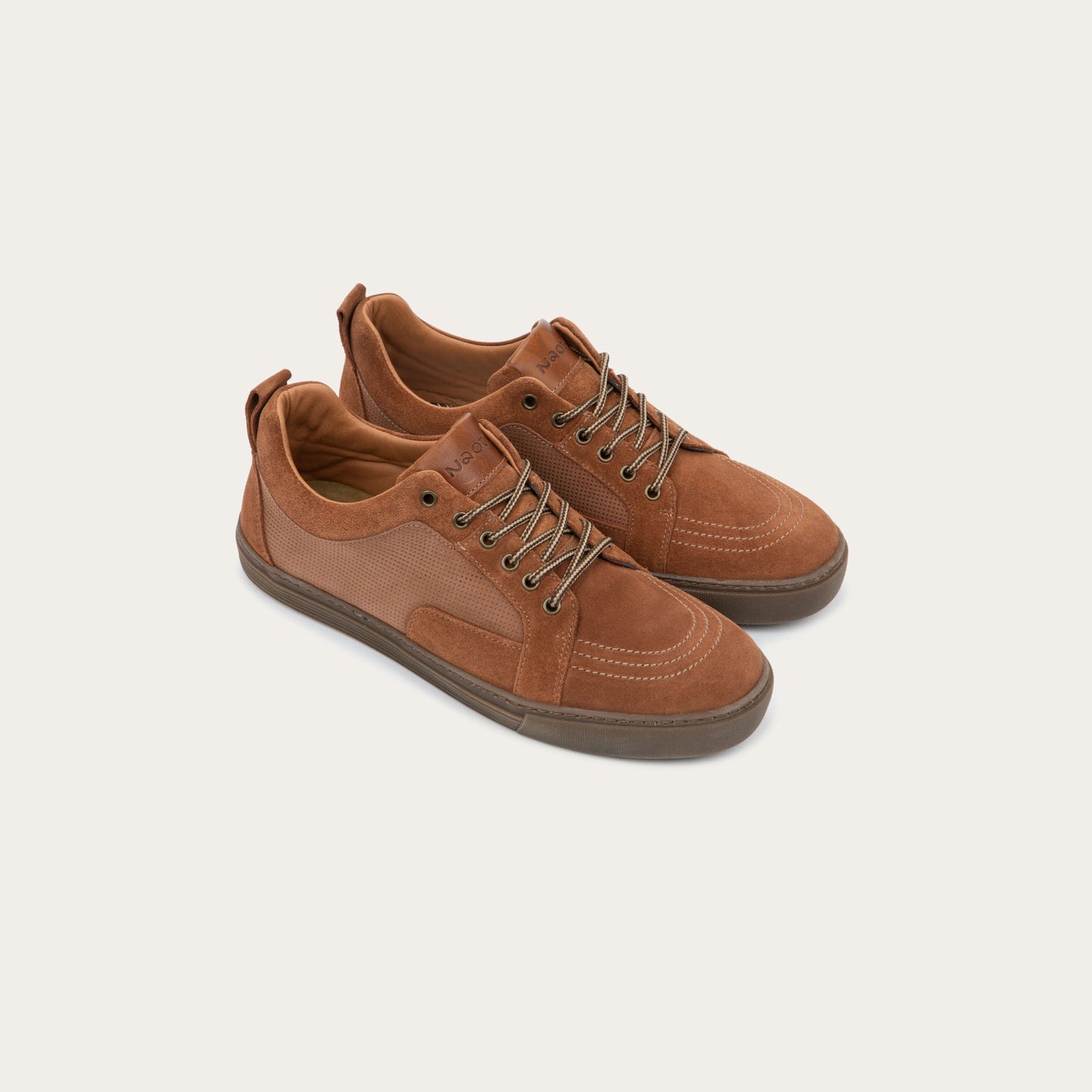 Pair of brown suede and perforated leather sneakers with matching brown laces and a textured rubber soles.
