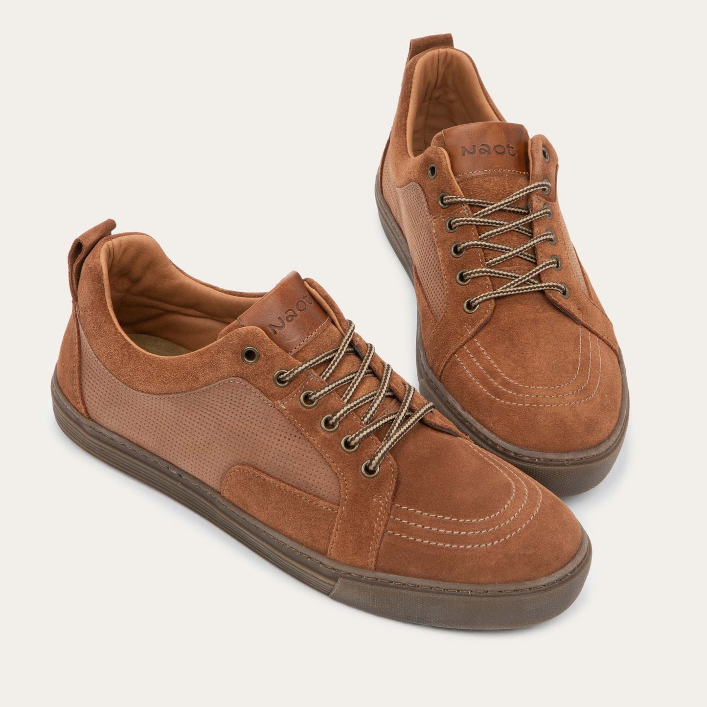 Pair of brown suede and perforated leather sneakers with matching brown laces and a textured rubber soles.