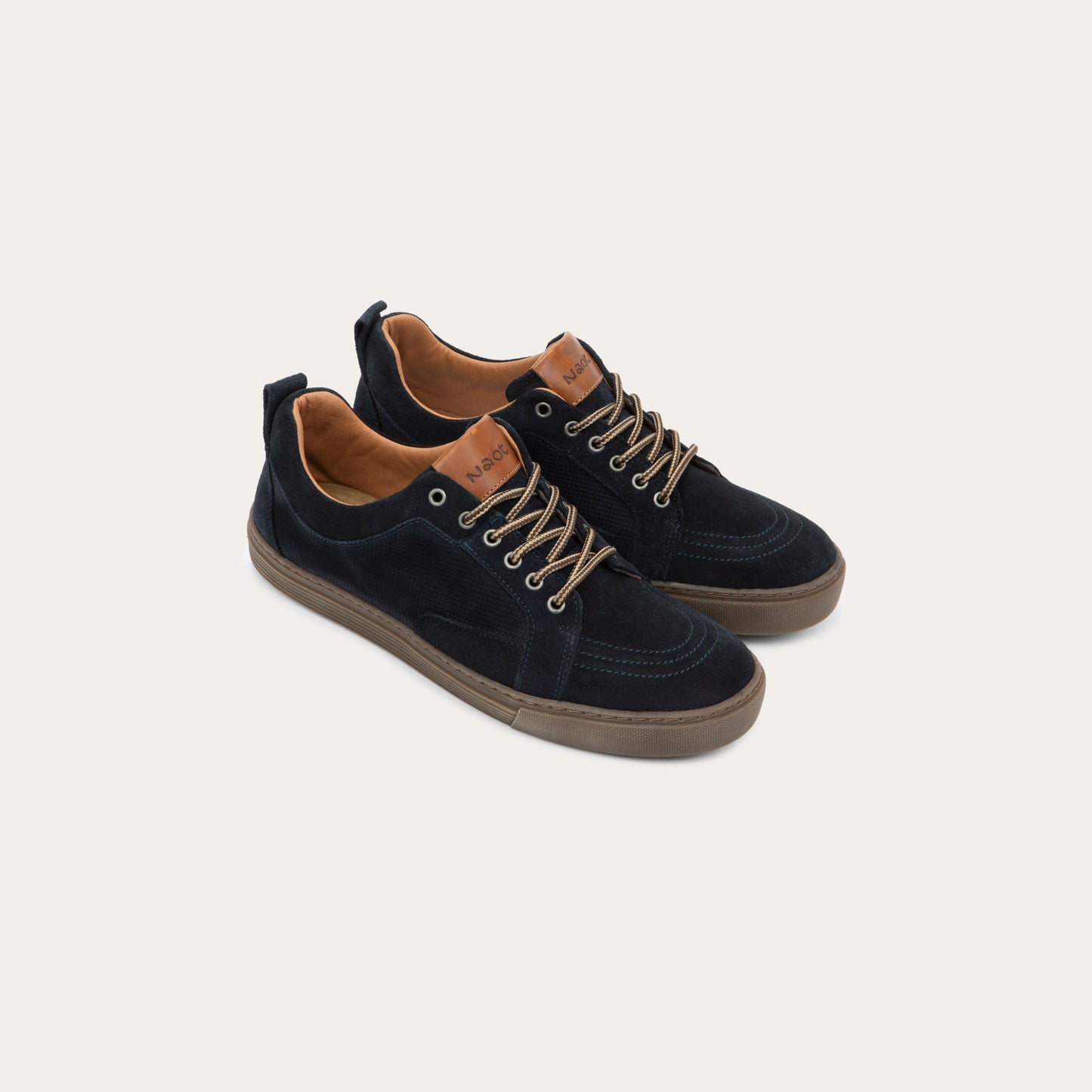 Pair of  black low-top sneakers with tan laces, brown soles, and tan interior linings. 