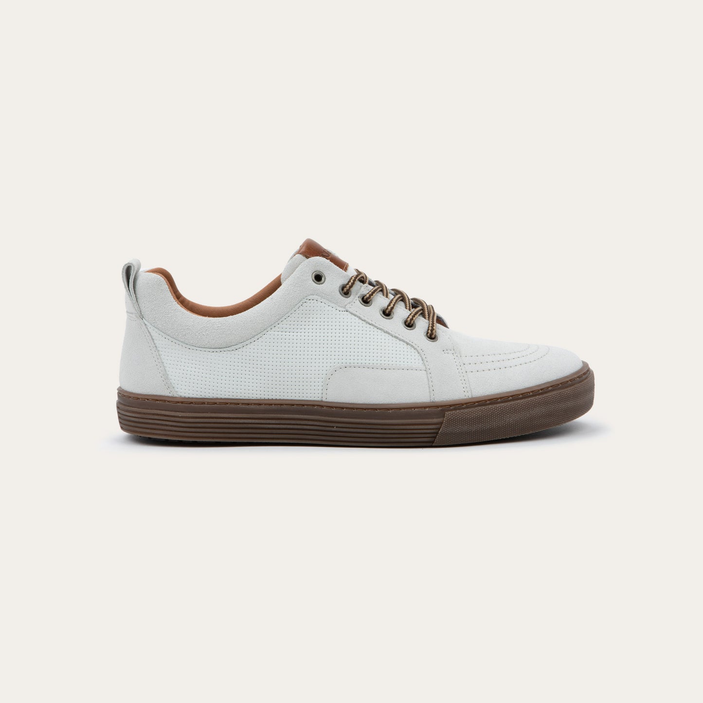 Profile view of a white low-top sneaker with brown laces, brown inner lining, and a brown rubber sole.