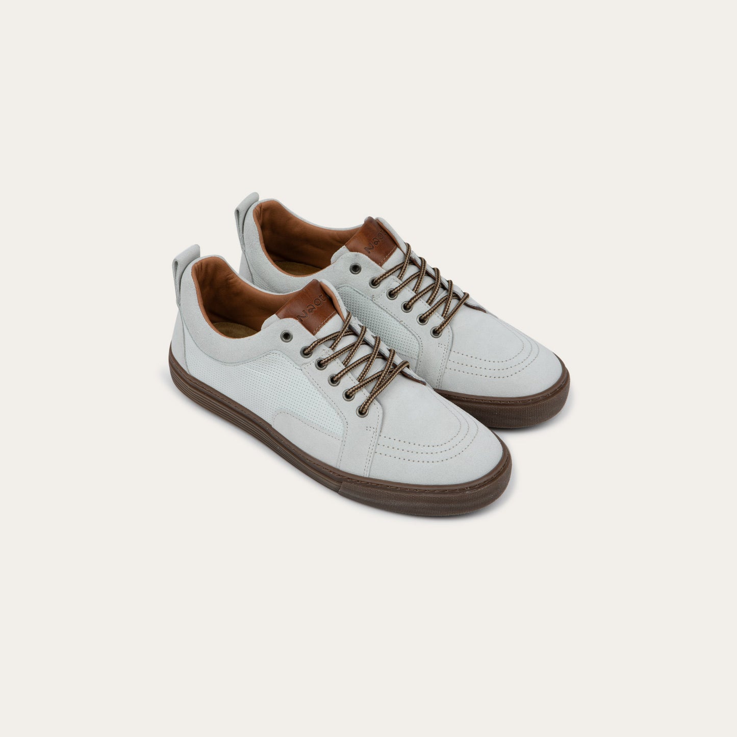Pair of  white low-top sneakers with brown laces, brown inner linings, and brown rubber soles.