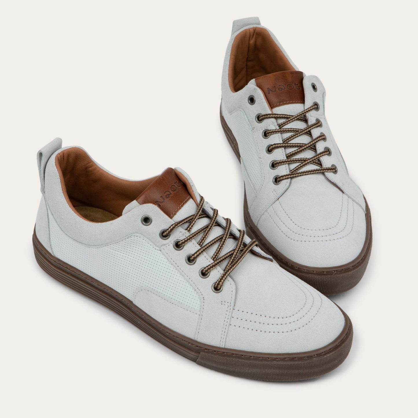 Pair of  white low-top sneakers with brown laces, brown inner linings, and brown rubber soles.