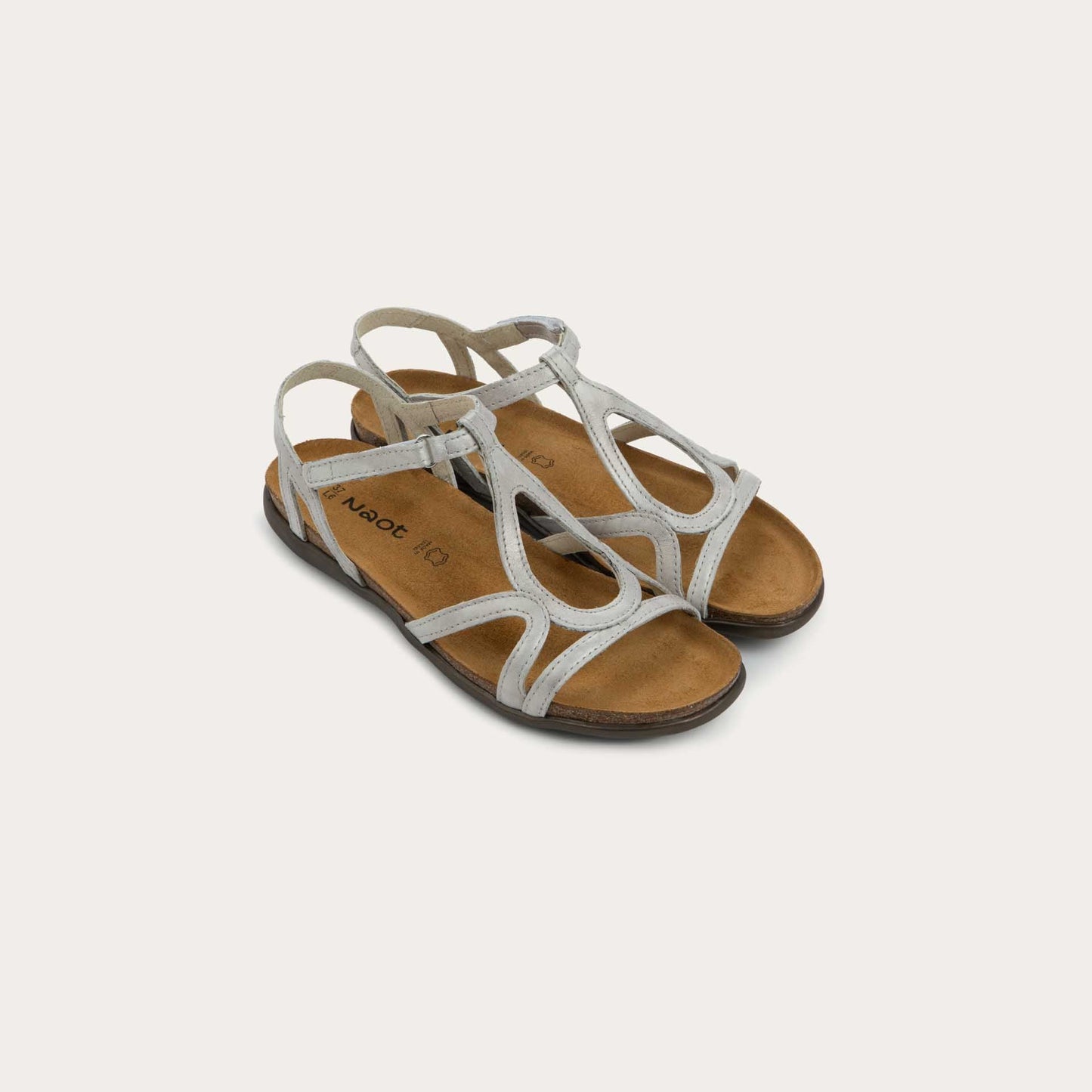 Pair of silver strappy sandals with an open-toe design and cork footbed on a brown sole