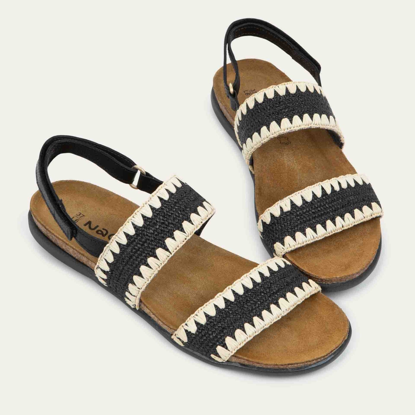 Pair of  black sandals featuring two textured toe straps and an adjustable ankle strap on a cork footbed.