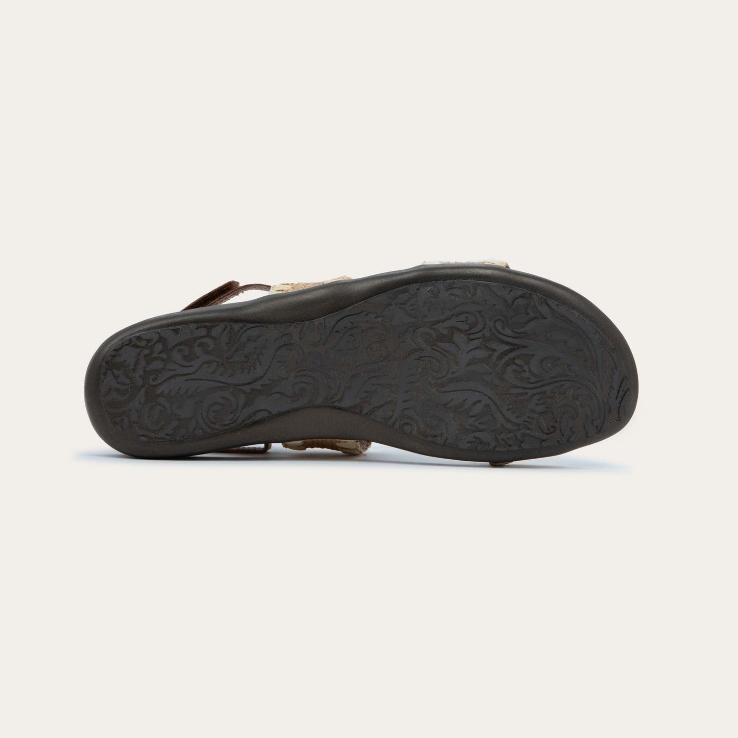 Bottom view of a brown sandal featuring two textured toe straps and an adjustable ankle strap on a cork footbed.