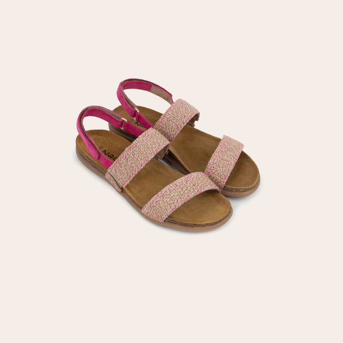 Pair of  pink sandals featuring two textured toe straps and an adjustable ankle strap on a cork footbed.